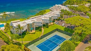 Een resort met een tennisbaan, zwembad en uitzicht op de oceaan.