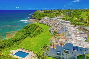 A resort with a pool, lush greenery, and ocean views.