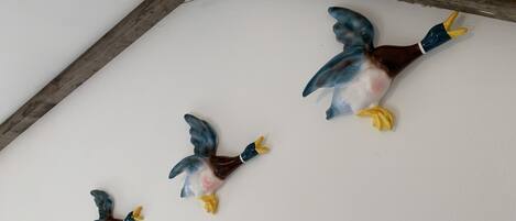 Three ceramic bird sculptures on a white ceiling.
