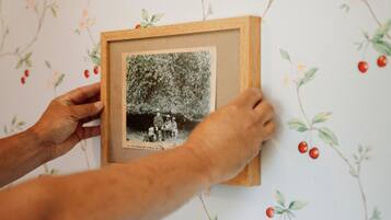 A framed photograph being hung on a wall with a floral wallpaper pattern.