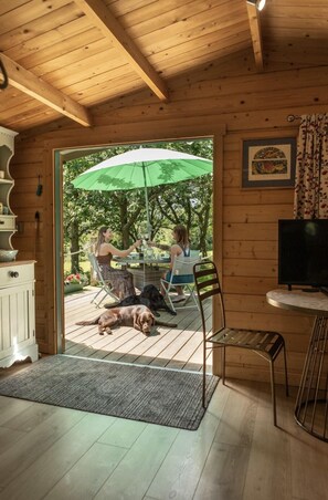 A wooden cabin interior with a dining area, a television, and a dog lying on the floor.