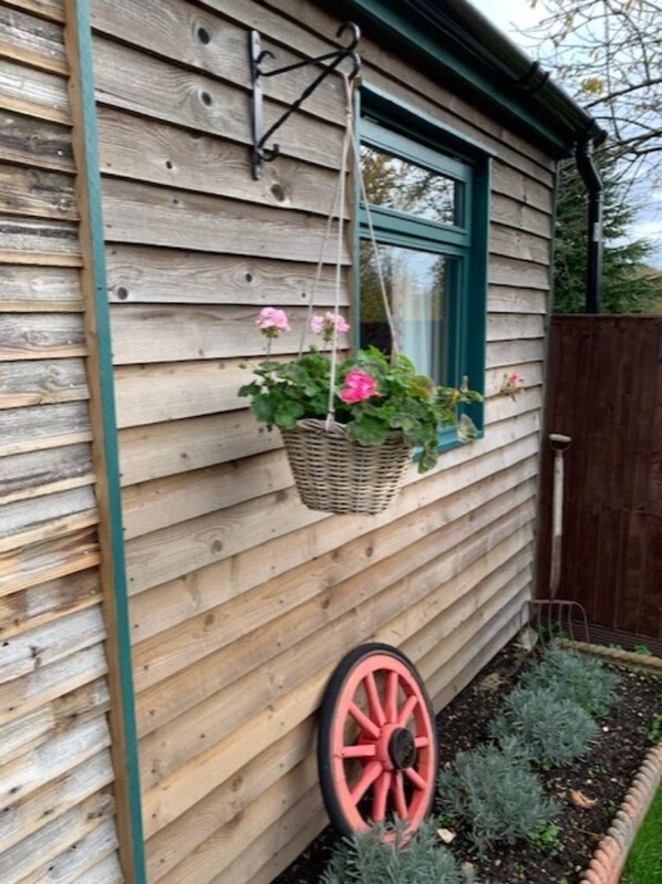 A wooden house with a window and a hanging basket with flowers.
