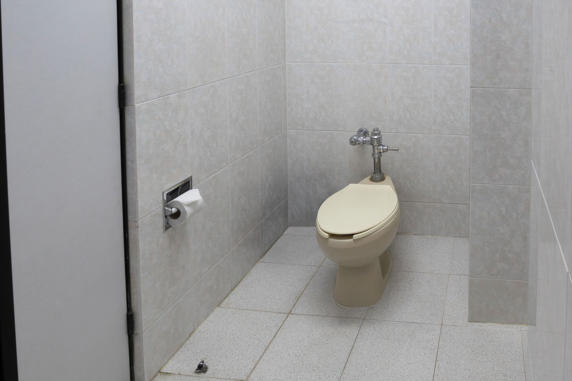 Un baño pequeño y moderno con inodoro, dispensador de toallas de papel y piso de baldosas.