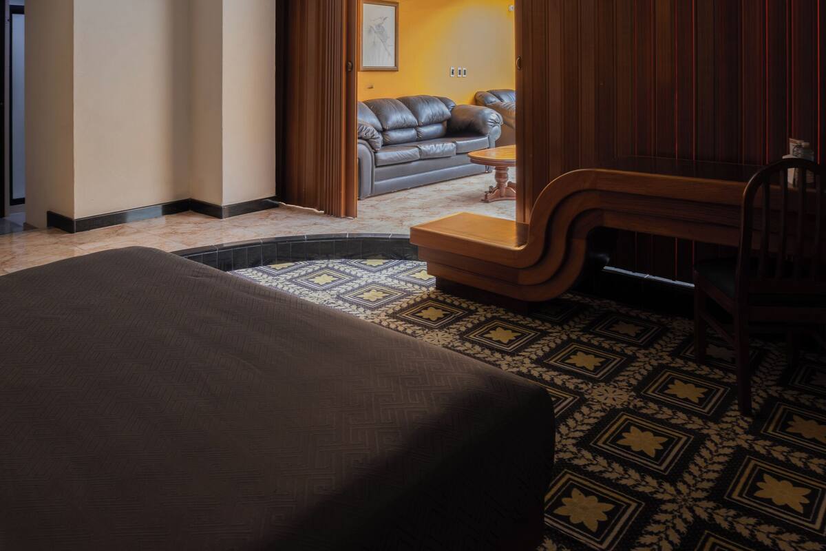 Een hotelkamer met een groot bed, een houten bankje, een kleine tafel en een bank op de achtergrond.