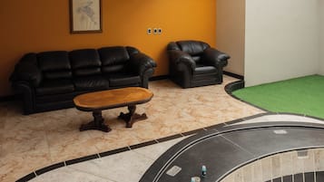 Una habitación con un sofá de cuero negro, una mesa de centro de madera y una pequeña zona de piscina.