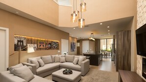 A spacious living area with a large L-shaped sectional sofa, a coffee table, and a flat-screen TV. There is a dining area with a table and chairs, and a kitchen in the background. - Near Disney/Entire Home/Parking/Wi-Fi/Great Lay Out/BBQ Grill/Heated Pool Shared (Kissimmee)