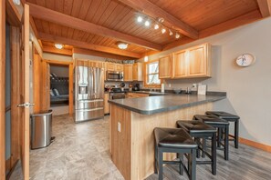 Una cocina moderna con armarios de madera, electrodomésticos de acero inoxidable y una isla central con taburetes de bar.