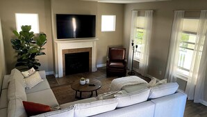 Una sala de estar con chimenea, un televisor de pantalla plana grande, un sillón de cuero y un sofá.