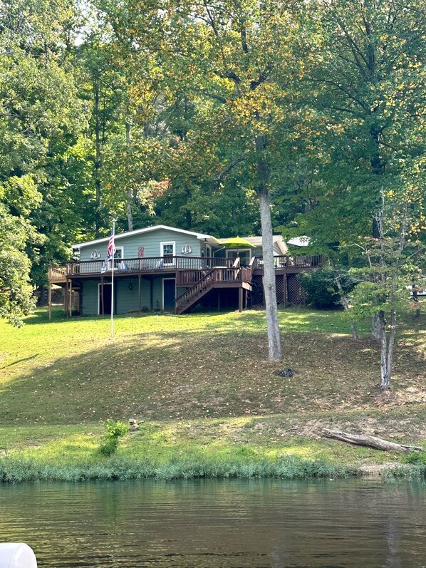 A lakeside cabin with a deck and a flagpole.
