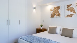 Ein Schlafzimmer mit einem Bett, einem Nachttisch, einer Topfpflanze und Wandbildern.