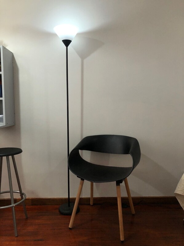 A modern room with a black chair, a tall floor lamp, and a small stool. - Boutique in Heredia (Cerca de Todo - Close to everything) (Heredia)