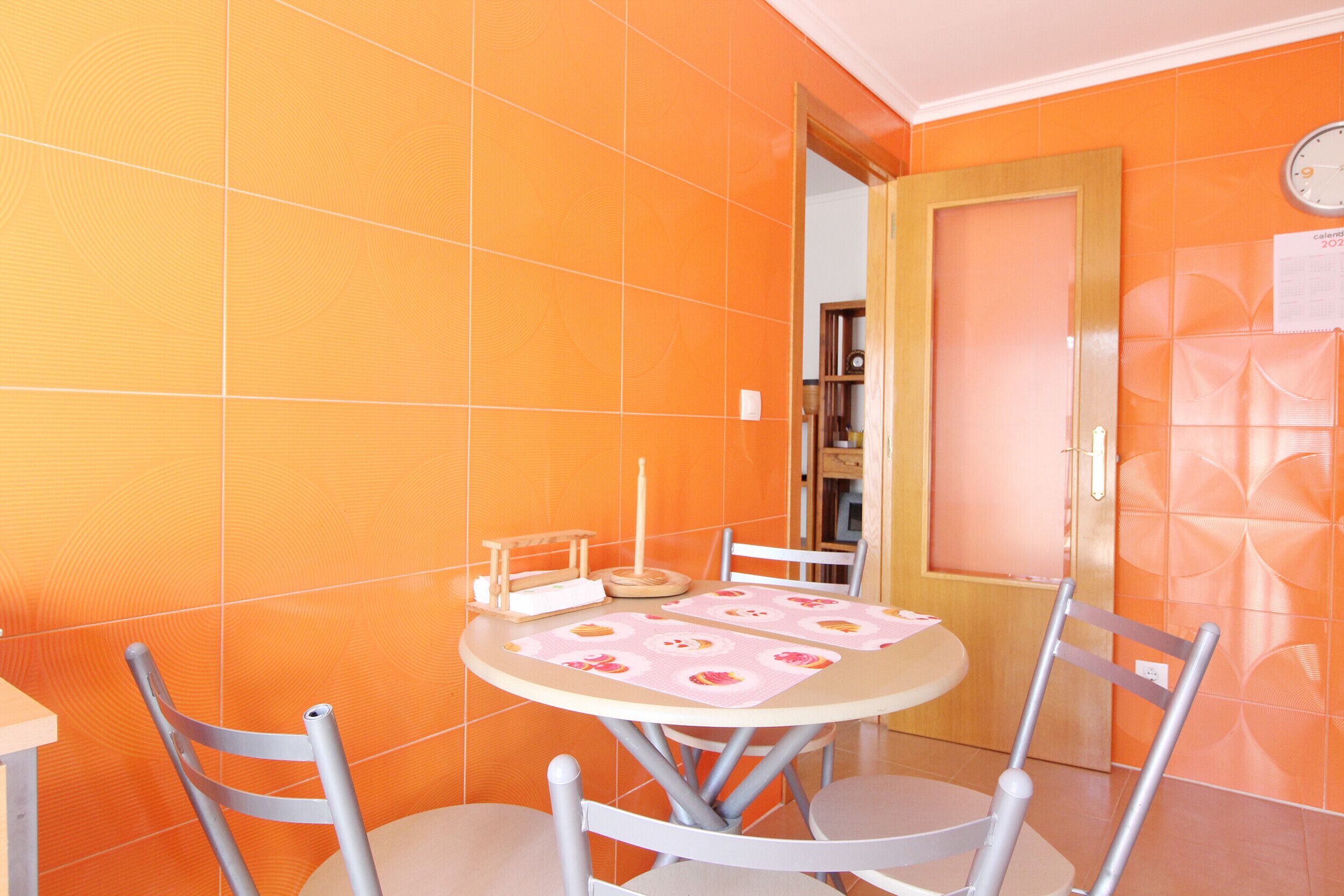 Un comedor con una mesa redonda, cuatro sillas y un reloj de pared.