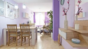 Ein modernes Wohnzimmer mit Essbereich, ausgestattet mit einer Couch, Sesseln, einem Couchtisch und einer Topfpflanze.
