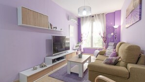 Ein Wohnzimmer mit Fernseher, Sofa und kleinem Tisch.