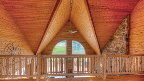 Un intérieur en bois avec un plafond haut, un mur en pierre et une rambarde en bois.