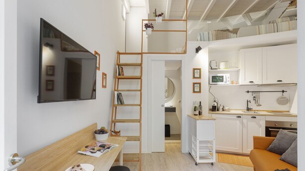 Een klein woongedeelte met een vide, een kitchenette en een eethoek.