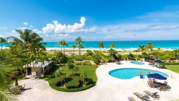 Un resort con piscina, palme e vista sulla spiaggia.