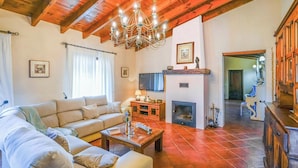 A living room with a sofa, coffee table, fireplace, and wooden ceiling beams.