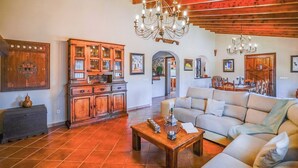 A spacious living room with a sofa, wooden cabinet, and a chandelier.