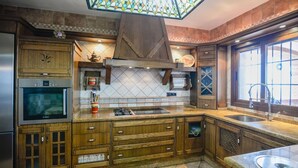 A kitchen with wooden cabinets, a Bosch oven, a microwave, a gas stove, and a large window. - Villa Biznaga Mijas by Ruralidays (Málaga)