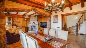 A cozy living room with a fireplace, wooden furniture, and a TV. - Villa Biznaga Mijas by Ruralidays (Málaga)