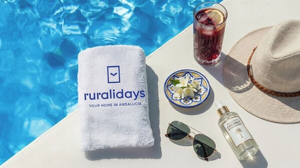 Ambiente de piscina com toalha, bebida, óculos de sol, chapéu e um frasco de névoa pós-sol.