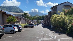 A parking lot with cars, a building with solar panels, and a mountain in the background.