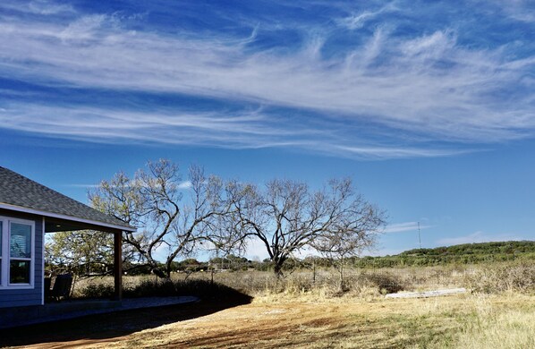 A house with a porch, a clear sky, and a dry landscape. - HOT TUB! Outdoor Shower, New Construction, Views (Fredericksburg)