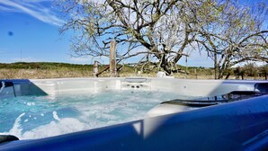 A hot tub with a view of a tree and a fence in the background.