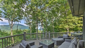 A deck with wicker furniture and a glass table, overlooking a forested area with a mountain in the distance. - Luxe Big Canoe Resort Home w/ 3 Decks & Mtn Views! (Jasper)