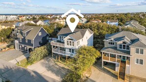 A residential area with houses, a waterfront, and a prominent house icon indicating a location. - 1755 - Don't Worry Beach Happy - Walk to Beach | Pool, Hot Tub & Tiki Bar (Corolla)