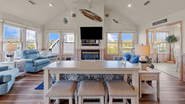 A spacious living room with a large island, a fireplace, and a ceiling fan. - 1755 - Don't Worry Beach Happy - Walk to Beach | Pool, Hot Tub & Tiki Bar (Corolla)