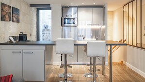 A modern kitchen with white cabinets, stainless steel appliances, and two bar stools. - Superb quality duplex in hypercentre with rooftop and air conditioning (Bordeaux)