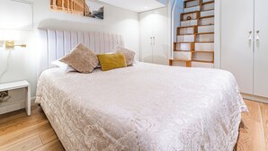 Une chambre à coucher avec un grand lit, une table de chevet, une armoire et une bibliothèque intégrée.