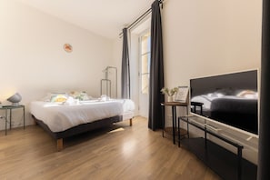Une chambre moderne avec un lit, des tables de chevet, une télévision et une fenêtre avec des rideaux.