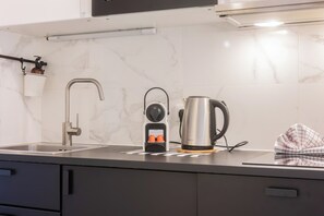 Een keuken met een moderne kraan, een waterkoker en een koffiezetapparaat op het aanrecht.
