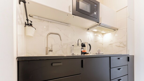 Een moderne keuken met een ingebouwde magnetron, waterkoker en koffieapparaat.