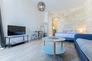 Een moderne woonkamer met een flatscreen televisie, een bank, een eettafel en een stenen muur.