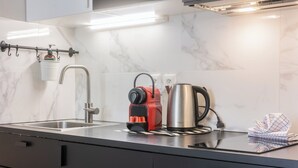 A modern kitchen with a stainless steel sink, a red electric kettle, and a stainless steel coffee pot.