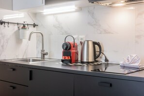 Une cuisine moderne équipée d’un évier en acier inoxydable, d’une bouilloire électrique rouge et d’une cafetière en acier inoxydable.