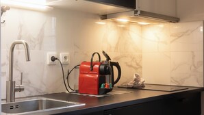 A modern kitchen with a stainless steel sink, a red coffee maker, and a marble backsplash. - Beautiful renovated apartment for 2 in front of the Gare Saint-Jean (Bordeaux)