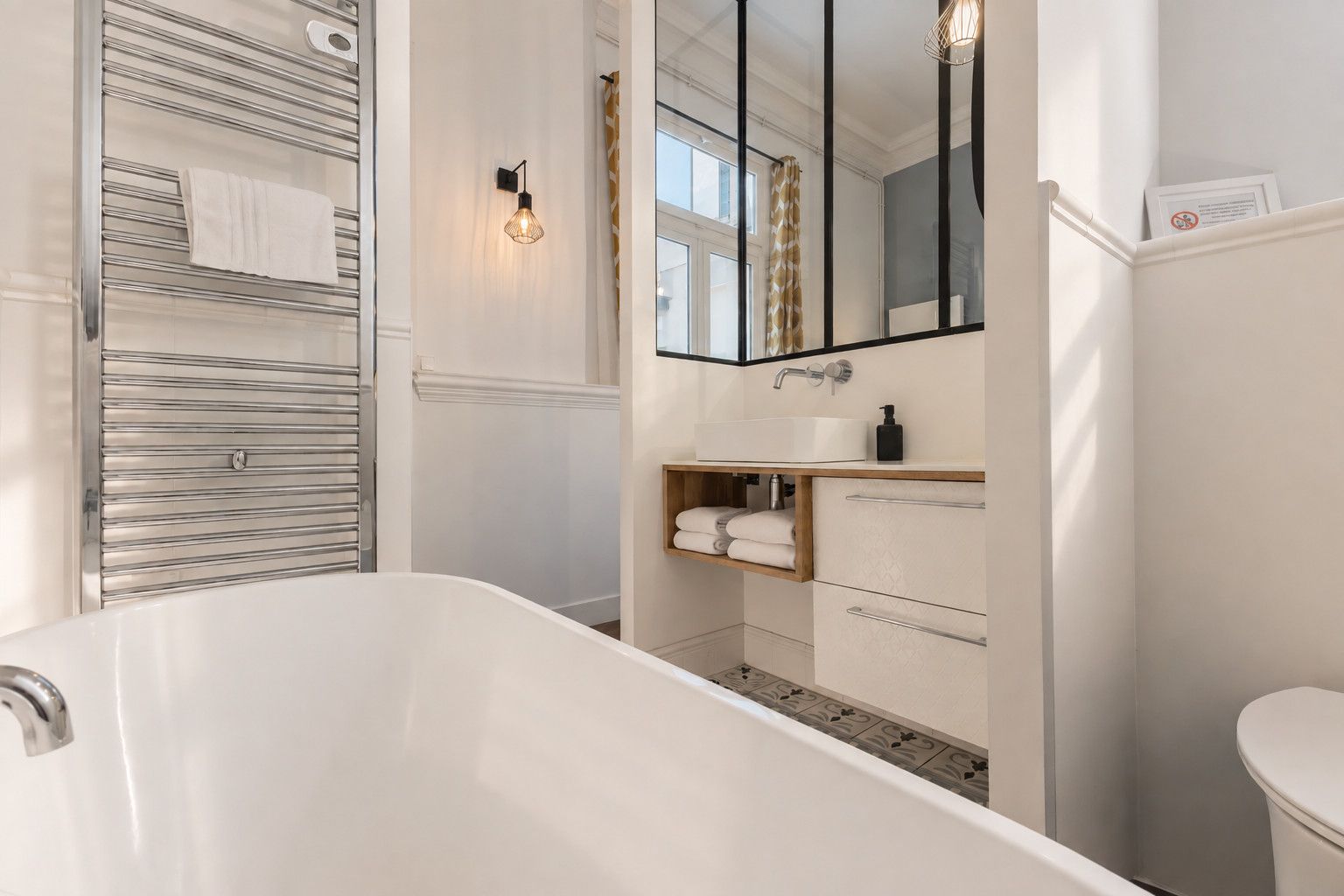 A modern bathroom with a freestanding bathtub, a vanity with a mirror, and a towel rack.