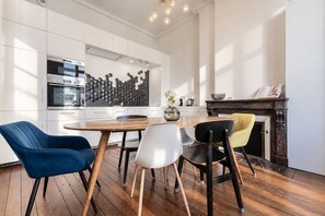 A modern kitchen with white cabinetry, a central island, and a dining area with a wooden table and chairs.