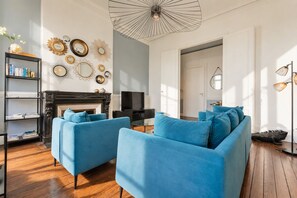 A living room with a fireplace, blue sofas, a bookshelf, and decorative mirrors.