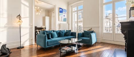 Un salón amplio con un sofá azul, una mesa de centro y una lámpara de pie.
