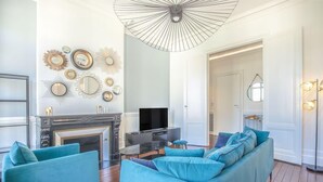 Una sala de estar con chimenea, un conjunto de sofás, televisión y espejos decorativos en la pared.