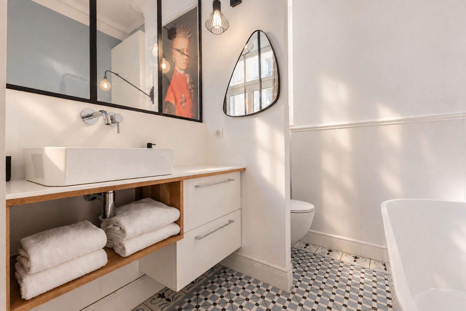 Een moderne badkamer met een witte wastafel, een houten opbergmeubel en een grote spiegel.