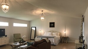 A spacious room with a large bed, a sofa, a dining table, and a TV. - Wellington Guest Suite (Wellington)