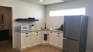 A modern kitchen with white cabinets, a stainless steel refrigerator, and a microwave. - Wellington Guest Suite (Wellington)