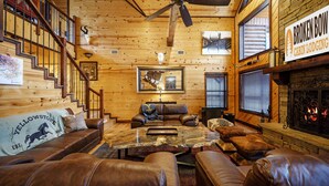 Et sommerhusinteriør med træpaneler, lædermøbler, en pejs og et skilt med teksten "Broken Bow Cabin Lodging".
